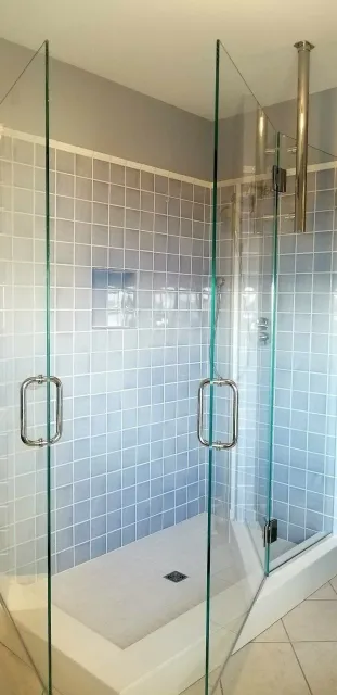 A bathroom with a walk in shower and a glass shower door.