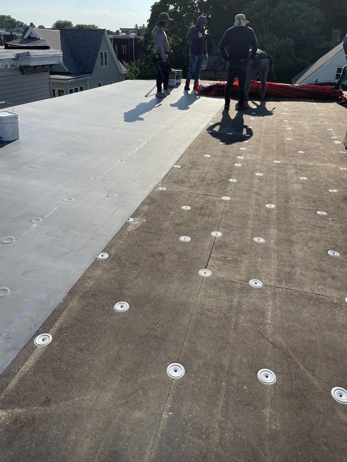 Storm King Roofing crew installing an EPDM flat membrane roof on a residential building in Revere, MA