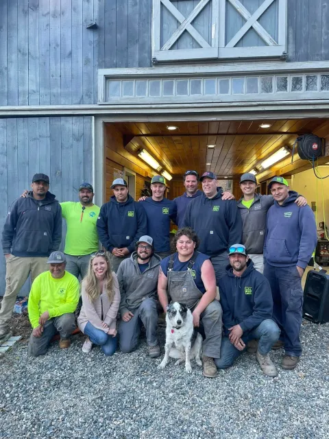 A group of people are posing for a picture in front of a barn.