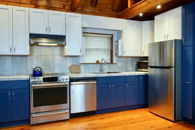 A kitchen with blue cabinets and stainless steel appliances