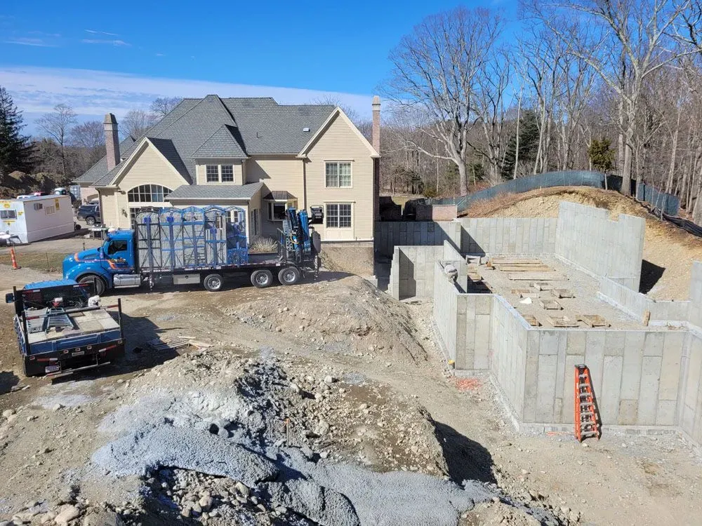 A blue truck is parked in front of a house under construction.
