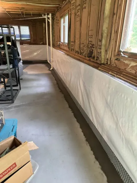 Unfinished hallway with exposed wall studs, insulation, and covered lower wall in a narrow interior space