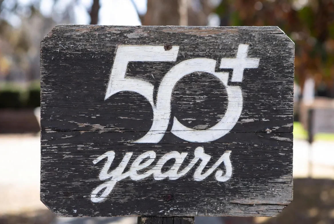 Weathered wood sign reading “50+ years”
