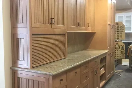 A finished kitchen remodel featuring wooden cabinets and marble countertops and lots of storage space.