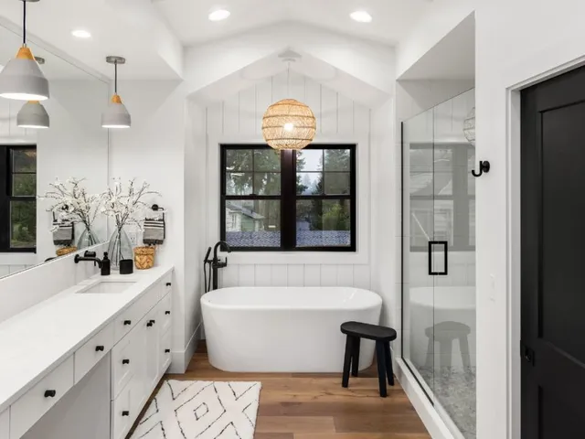 Modern remodeled bathroom with freestanding tub, glass shower, double vanity, and black accents
