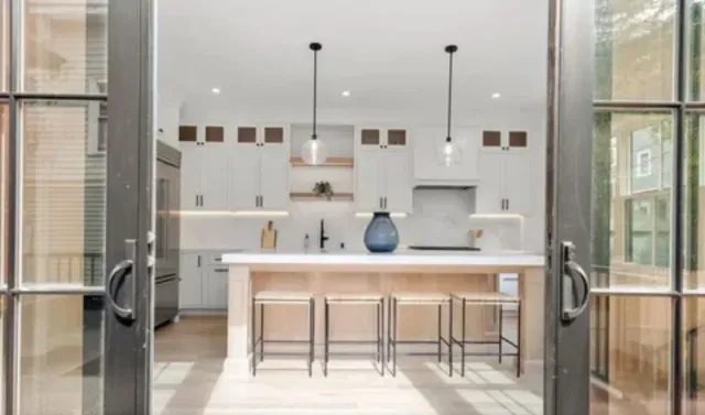 A kitchen with a large island and stools is visible through the sliding glass doors.
