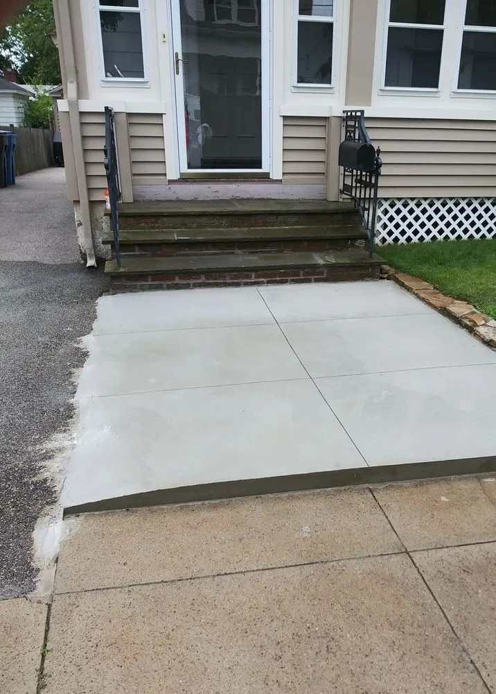 The same front walkway rebuilt as a clean new concrete walk and landing
