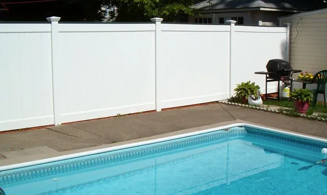 White PVC privacy fence enclosing a backyard pool