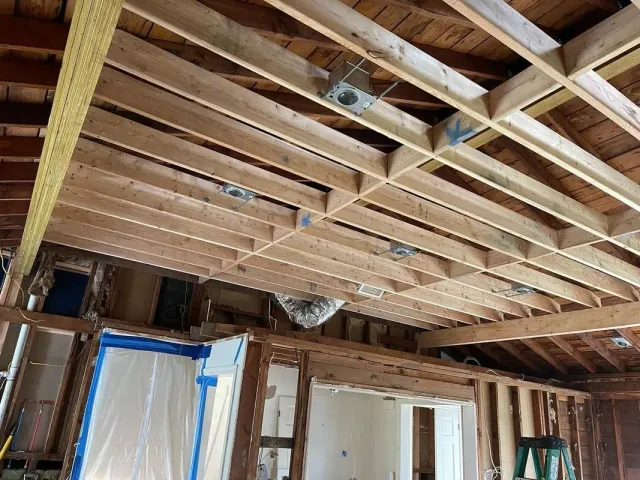 Ceiling and walls under construction with exposed wooden framing.