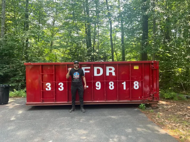 Alpha Haul crew beside a red roll-off dumpster