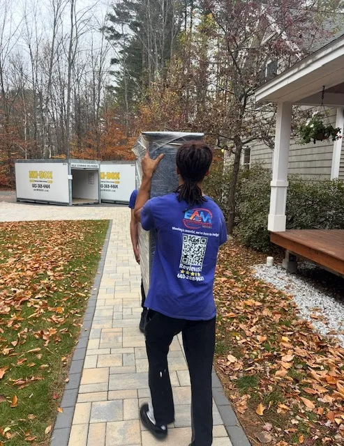 EAM Moving crew carrying stretch-wrapped furniture to a storage container in Meredith, NH