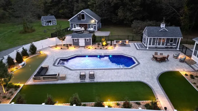 Backyard oasis with a custom in-ground pool, putting green, lounge seating, outdoor fire pit, and decorative landscape lighting