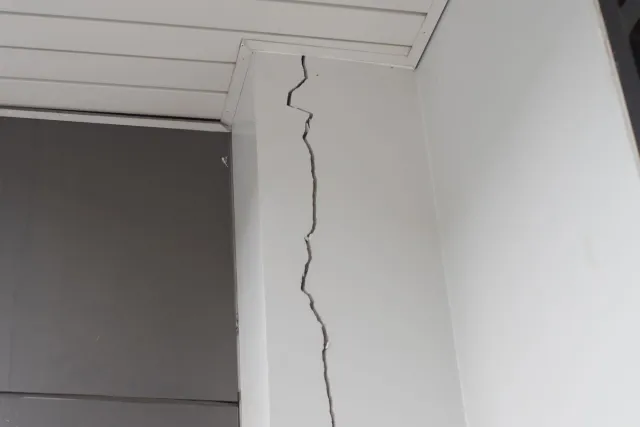 Tall interior wall with a long vertical crack near the ceiling