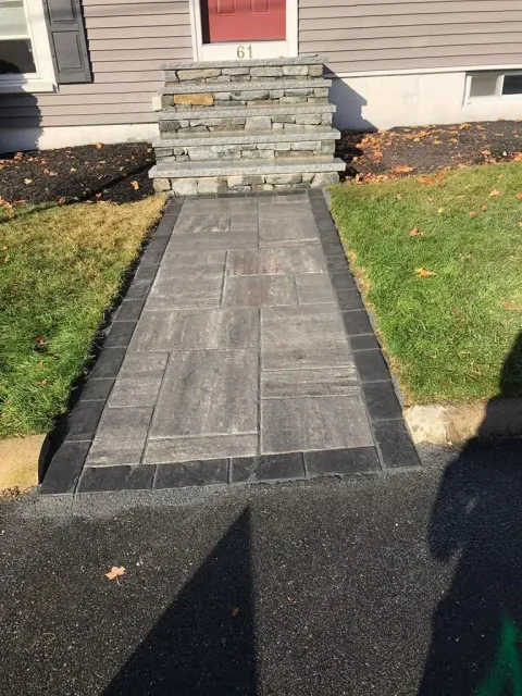 Front walkway with stone steps leading to a red front door, bordered by grass and mulch.