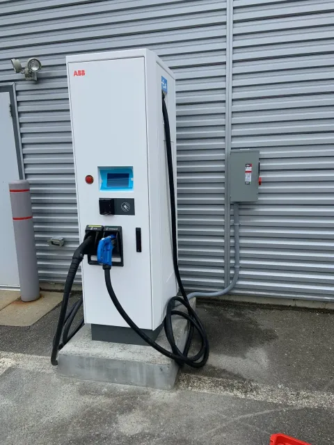 MJS Electrical Services - A white electric vehicle charging station is sitting in front of a building.