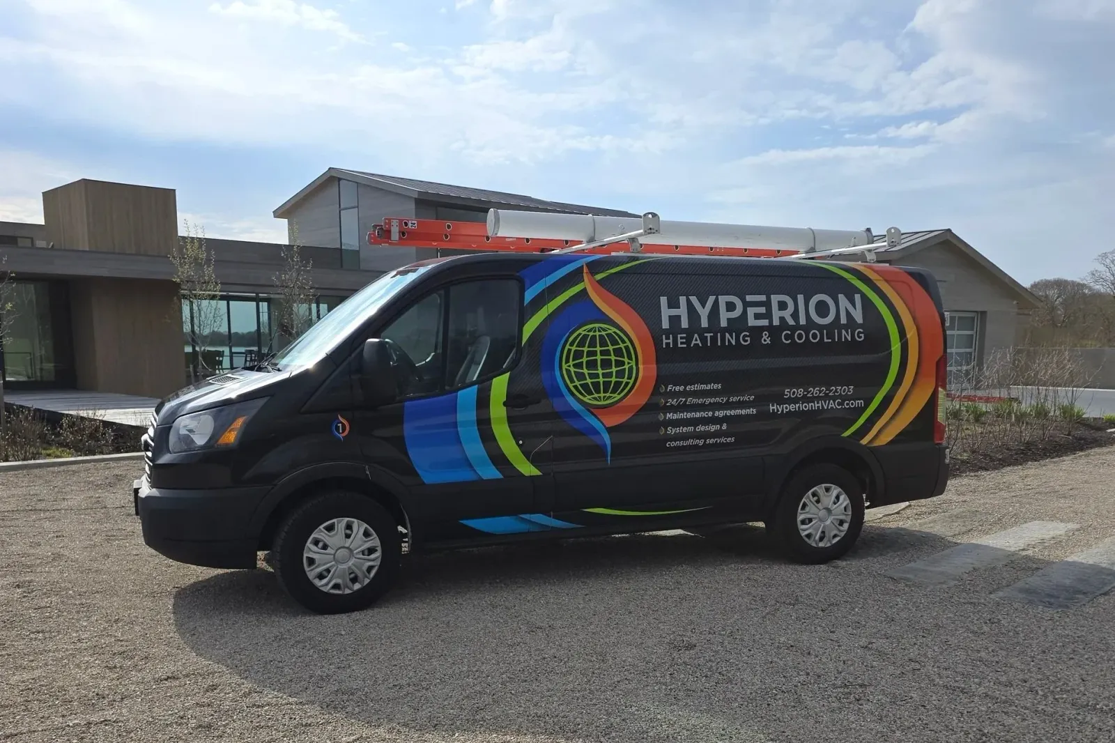 A Hyperion Heating & Cooling service van parked in front of a modern house with large windows and a sloped roof. The van is black with colorful graphics and text. It has a ladder on top.