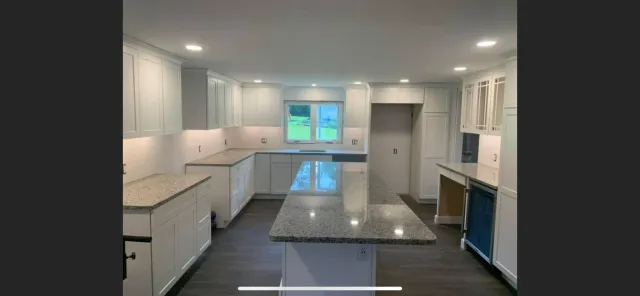 Modern kitchen renovation featuring white cabinets, granite countertops, and a window overlooking greenery, highlighting Next Step Property Services' kitchen remodeling expertise in Manchester, NH.