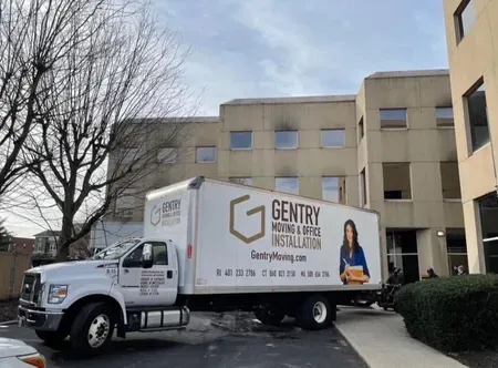 A Gentry moving truck parked outside a building, possibly loading/unloading.