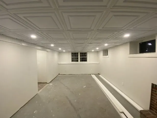 Finished basement with a patterned ceiling, recessed lights, and gray concrete floor.