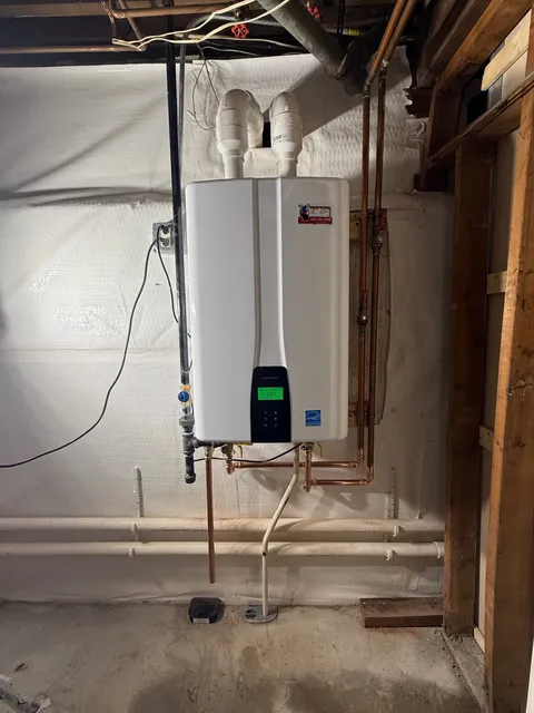 Navien high-efficiency tankless water heater installed in a Connecticut basement — clean copper manifold, PVC intake/exhaust, and endless hot water on demand.