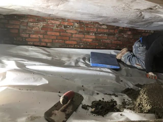 Crawl space encapsulation project with a moisture barrier and foundation work in progress