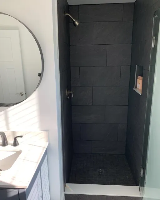 A bathroom with a shower , sink and mirror