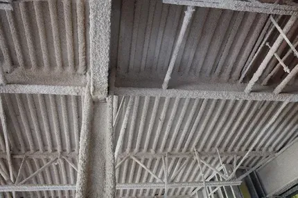 The metal ceiling of a building with a lot of fireproofing on it.
