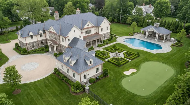 Large mansion with a well-manicured lawn, pool, and garden.