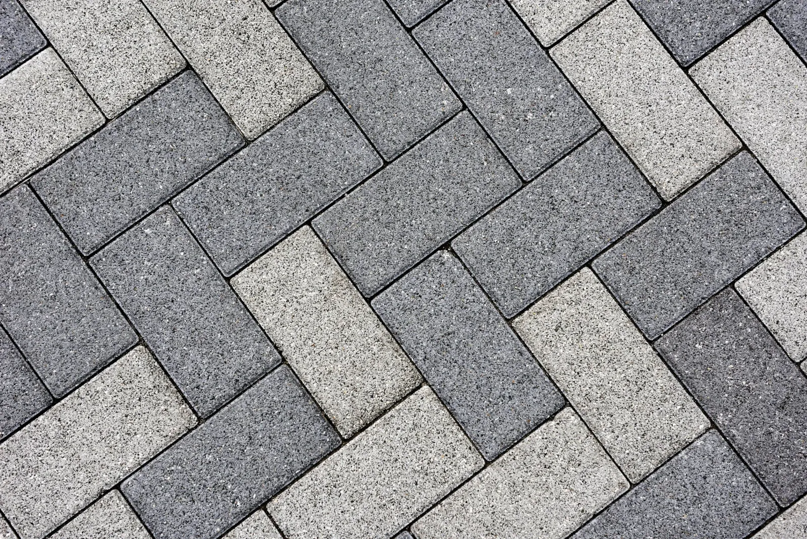 Gray and black rectangular paving stones arranged in a herringbone pattern.