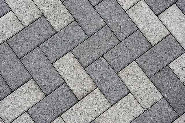 Gray and black rectangular paving stones arranged in a herringbone pattern.