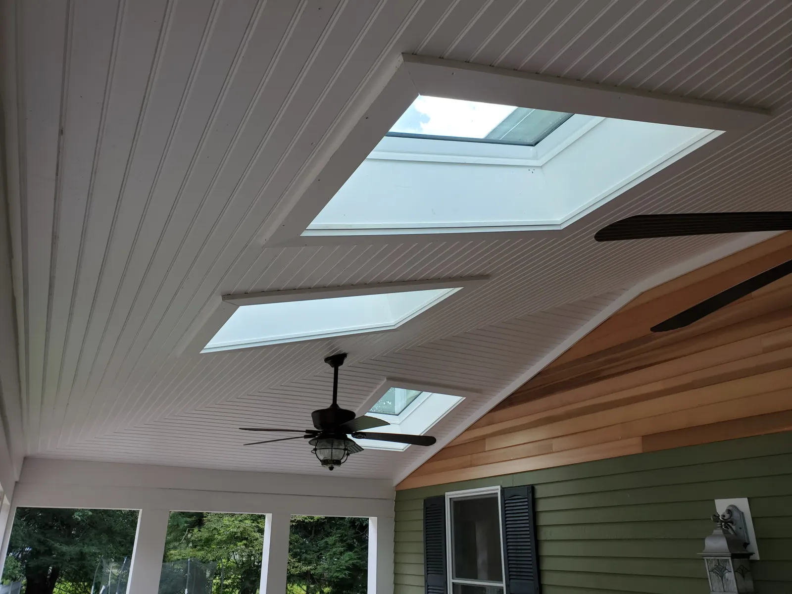 Covered porch ceiling with skylights and fan