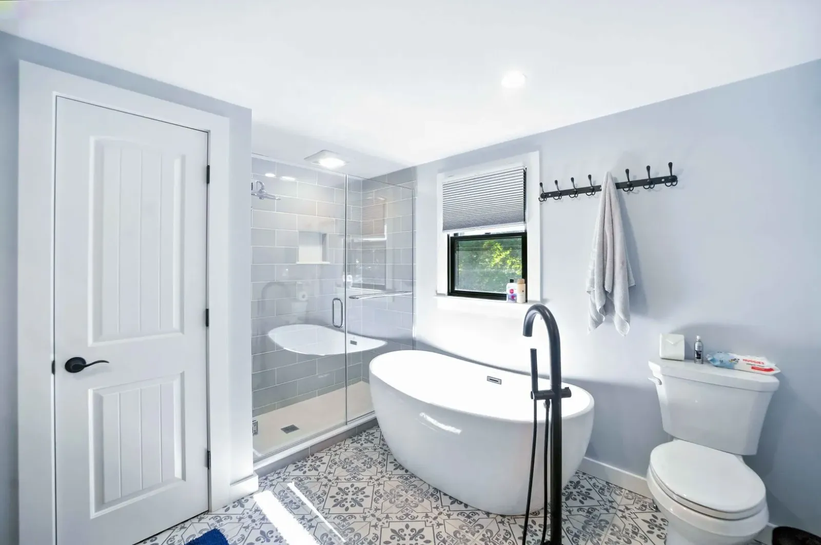 Bright modern bathroom with freestanding tub, walk-in shower, toilet, and gray-blue walls