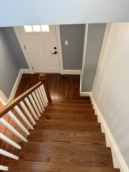 A clear view looking down a renovated staircase to a white front door as part of a Hopedale MA home remodel.
