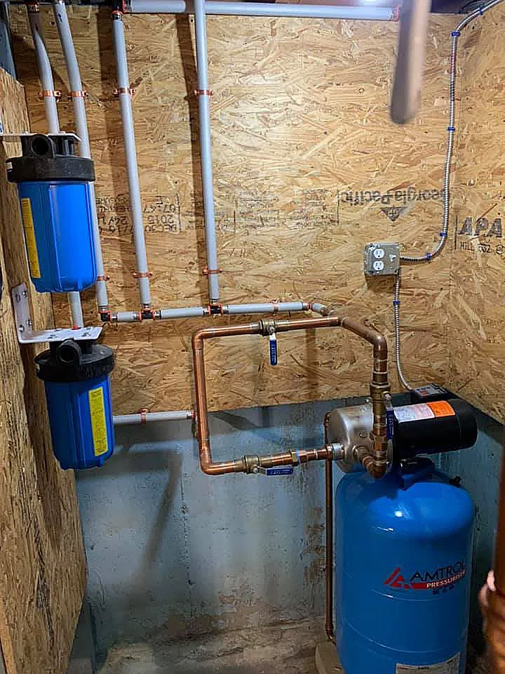 A room with a water pump , water filter , and copper pipes.