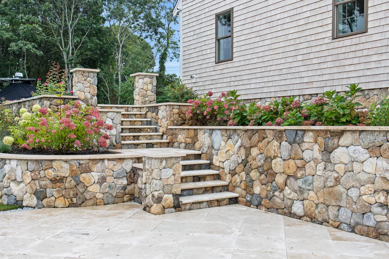 Natural stone retaining wall and stone step installation in Barnstable, Cape Cod by GADE Masonry & Landscaping.