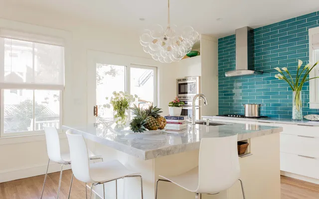 A kitchen with a center island and white chairs