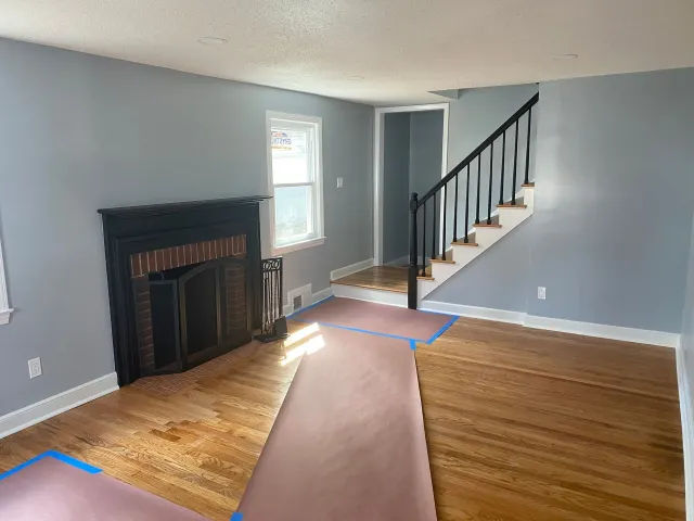 An empty living room with a fireplace and stairs.