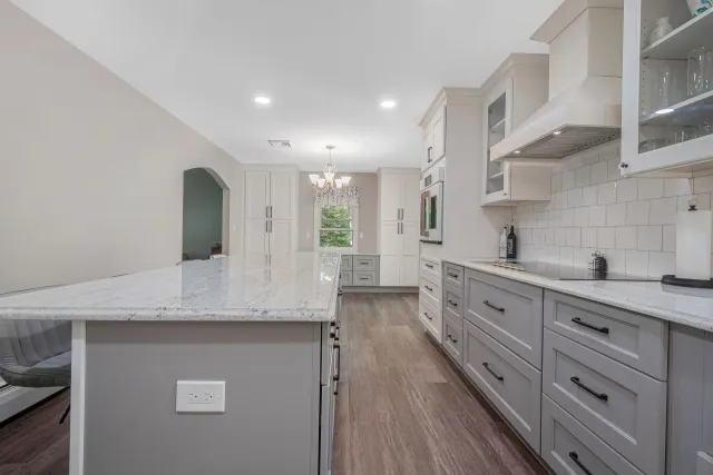 A kitchen with gray cabinets, white counter tops, and a large island