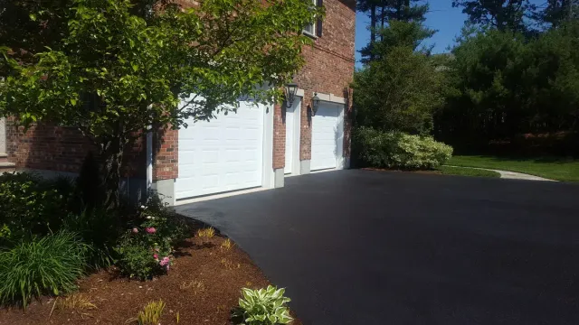 A driveway with two white doors and bushes