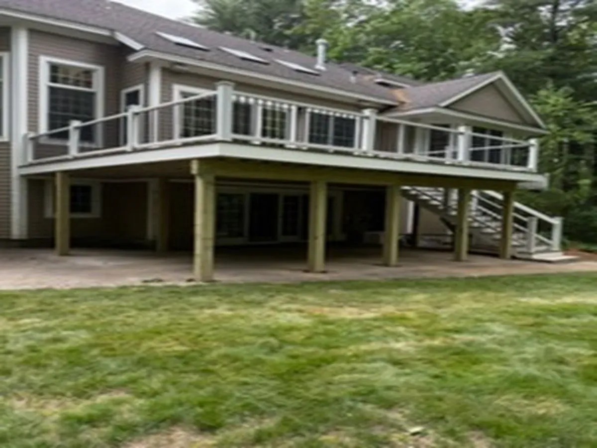 Raised backyard deck on a house with stairs and white railings over a grassy yard