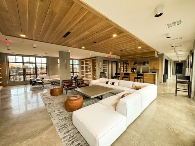Modern lounge area with couches, chairs and coffee table; natural light.