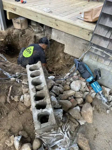SOS crew excavating to expose a failed sewer line outside a Rhode Island home