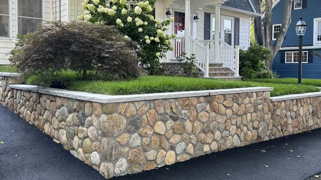 Custom stone retaining wall installation in Westwood, MA, showcasing durable and elegant landscaping solutions.