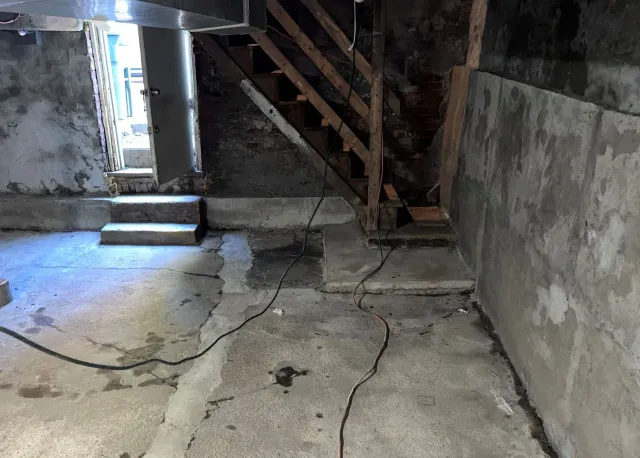 A basement with stairs and a wooden railing