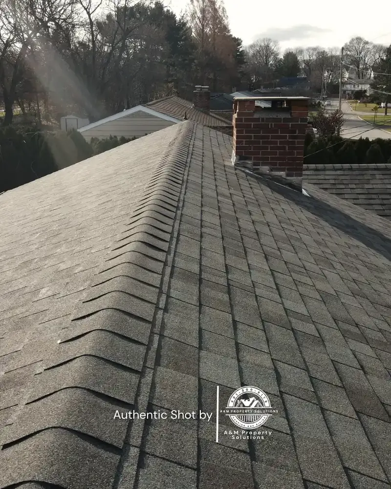 Aerial view along the ridge line of a newly completed asphalt shingle roof.