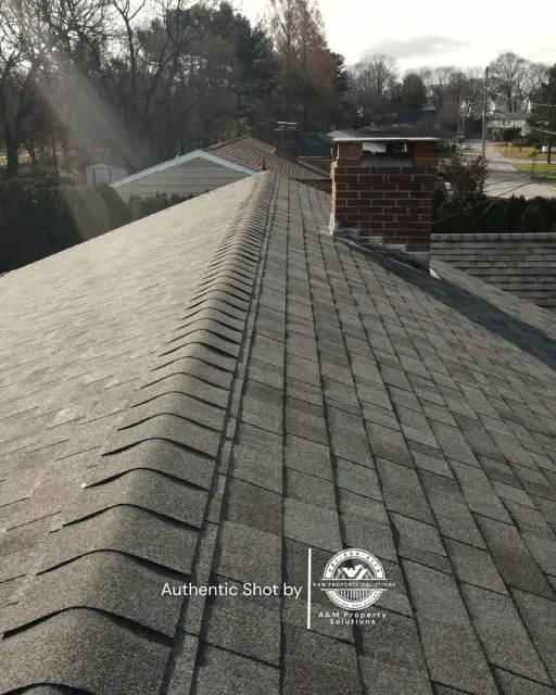 Aerial view along the ridge line of a newly completed asphalt shingle roof.