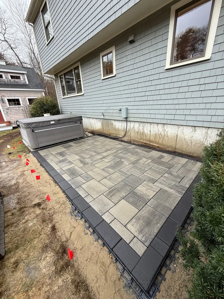 A paver patio with a hot tub at the end? That is how you make the most of crisp fall evenings.

This Plymouth project is coming together nicely, with a patterned blend of gray and taupe pavers framed by a charcoal border for a clean, finished look. The planting beds are marked out and evergreens are already in place, setting the stage for a backyard that feels like a private retreat. Patio design services like this are where hard work and detail really show, and our landscaping services cover everything from the base prep to the final planting.

• Custom paver patios and walkways built to last
• Irrigation system installation to keep new plantings healthy
• Residential landscaping designed around how you actually use your yard

If you have been thinking about a backyard upgrade in Duxbury, Kingston, or anywhere on the South Shore, fall is a great time to get started. Stop scrolling for a landscaper and reach out to South Shore Green Inc. to set up a consultation.