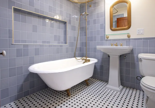 Bathroom renovation — blue tile surround, clawfoot tub and pedestal sink