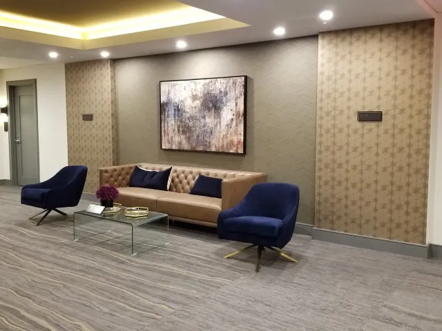 A living room with a couch, chairs, a coffee table and a painting on the wall