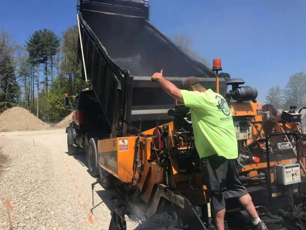 Asphalt paver with worker pointing to road surface